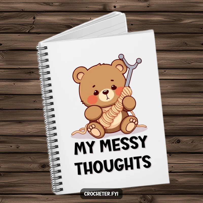 Funny notebook with a clumsy bear comically tangled in a huge crochet hook, ideal for jotting down crafting ideas humorously.