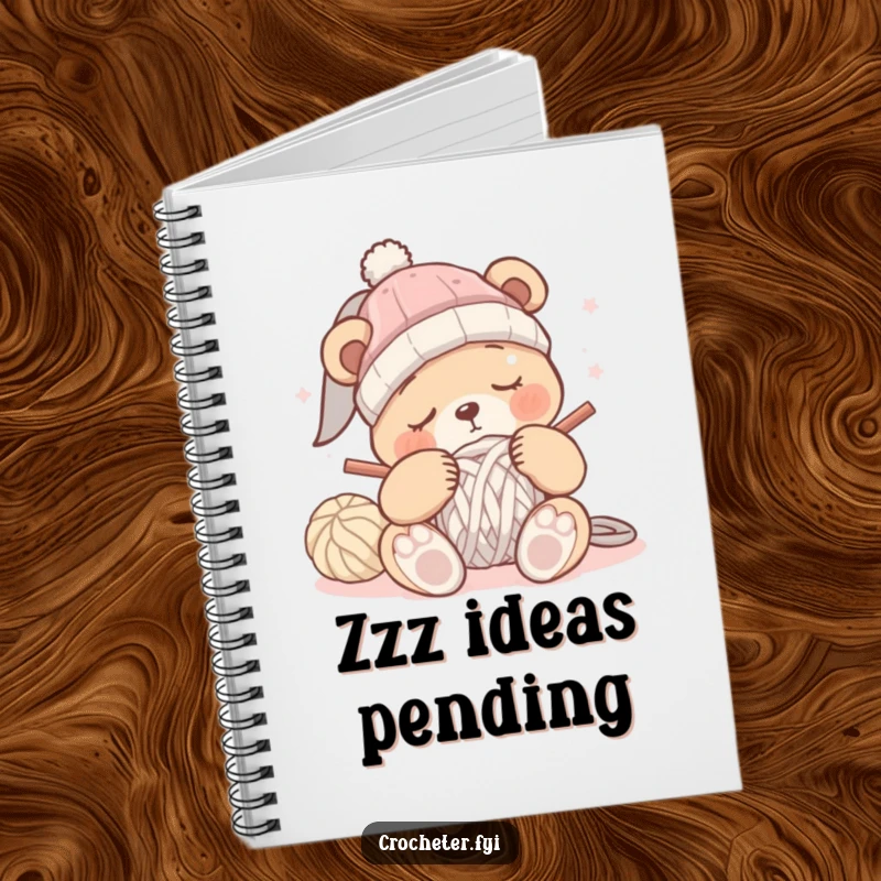 Funny sleepy bear crochet notebook with a bear dozing off while trying to crochet a hat, perfect for notes.