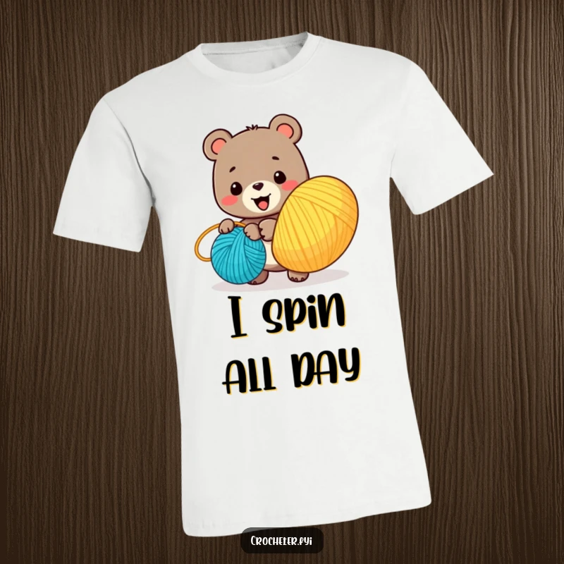 Funny t-shirt with a cheerful bear character joyfully winding a large, multi-colored ball of yarn, celebrating the art of crafting.