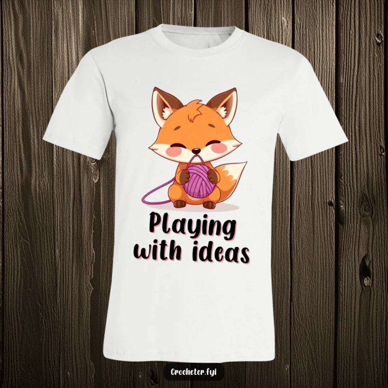 Funny t-shirt with a mischievous fox character expertly balancing a ball of yarn on its nose, showcasing playful dexterity.